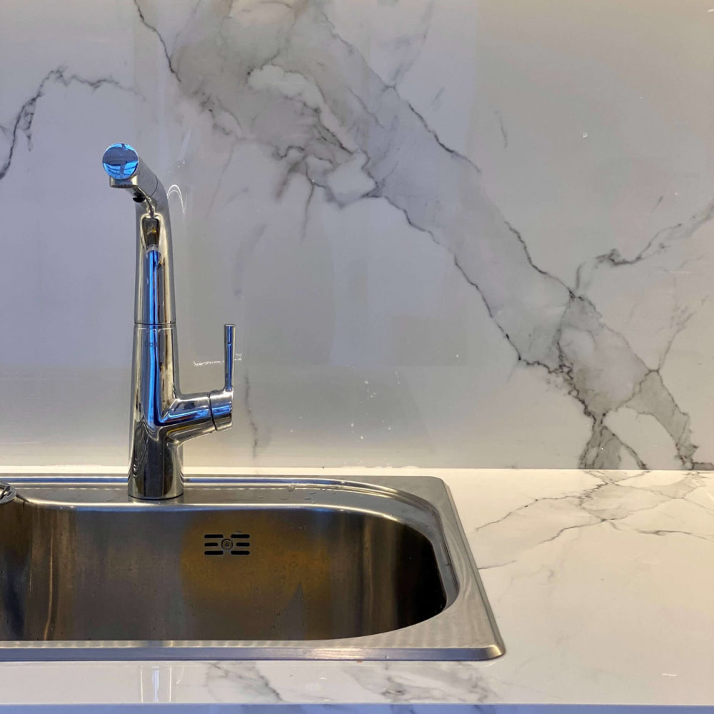 Detalle de mesada y revestimiento de fondo en Dekton calacatta natura.